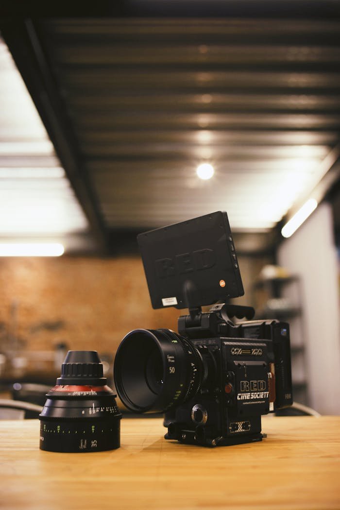 High-quality cinematic camera with detachable lens on table, showcasing filmmaking equipment.
