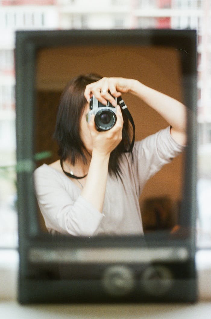 Woman taking a mirror selfie with a vintage camera indoors.