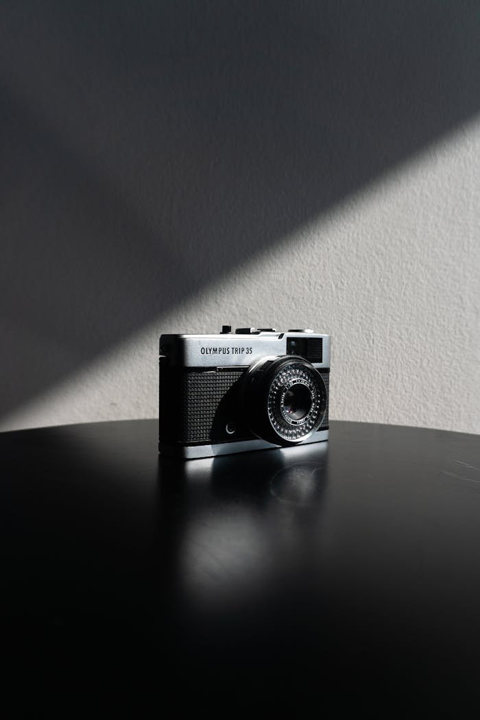 Close-up of a vintage Olympus Trip 35 camera in dramatic lighting on a black table.